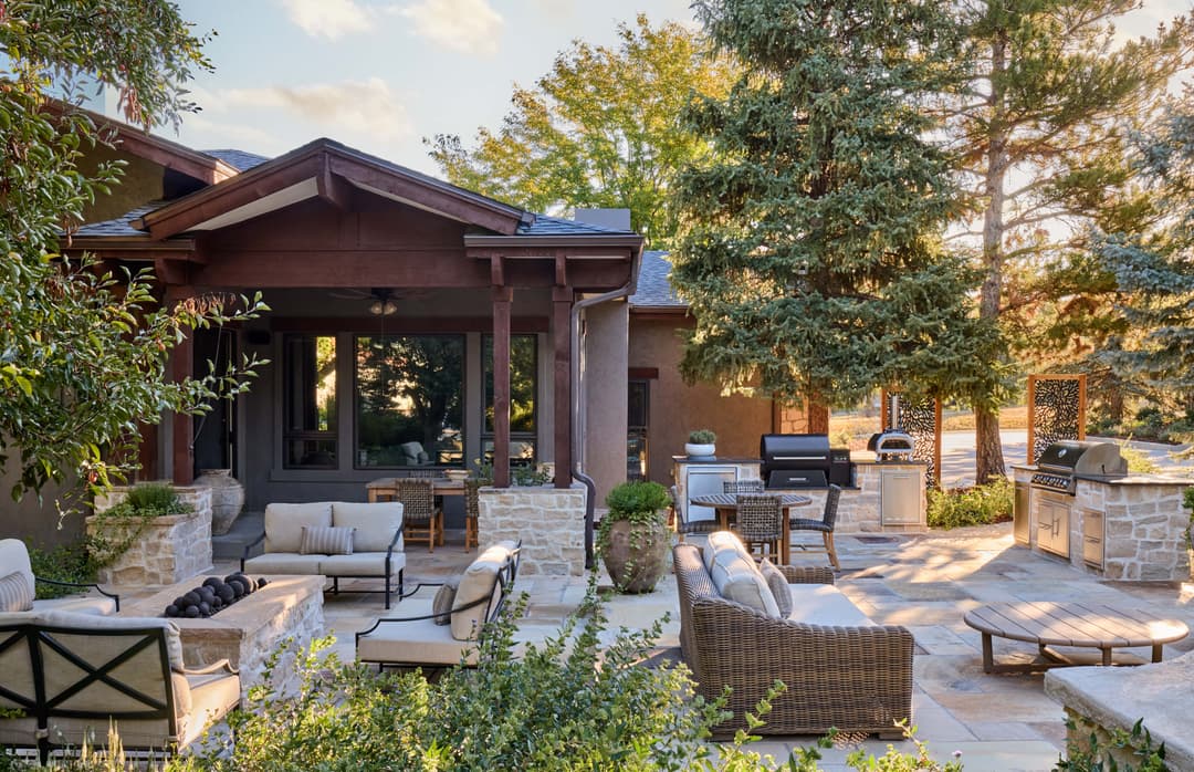 Cozy outdoor living space with seating, grill, and lush greenery in a serene setting.