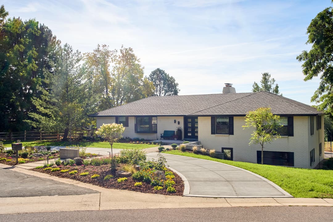 Modern single-story home with landscaped yard and driveway in a sunny suburban setting.