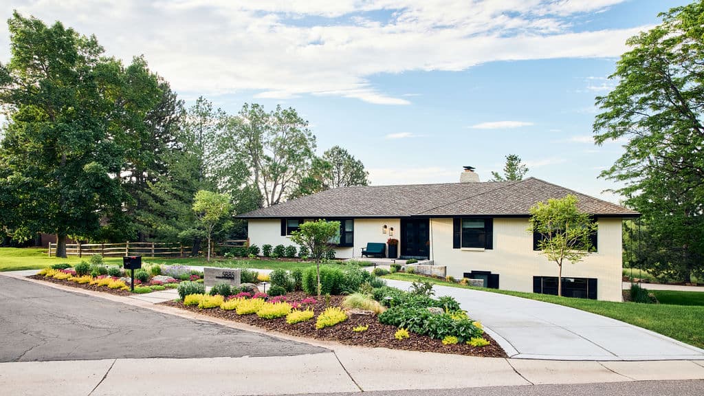 Single-story home with manicured garden and modern landscaping, surrounded by trees.