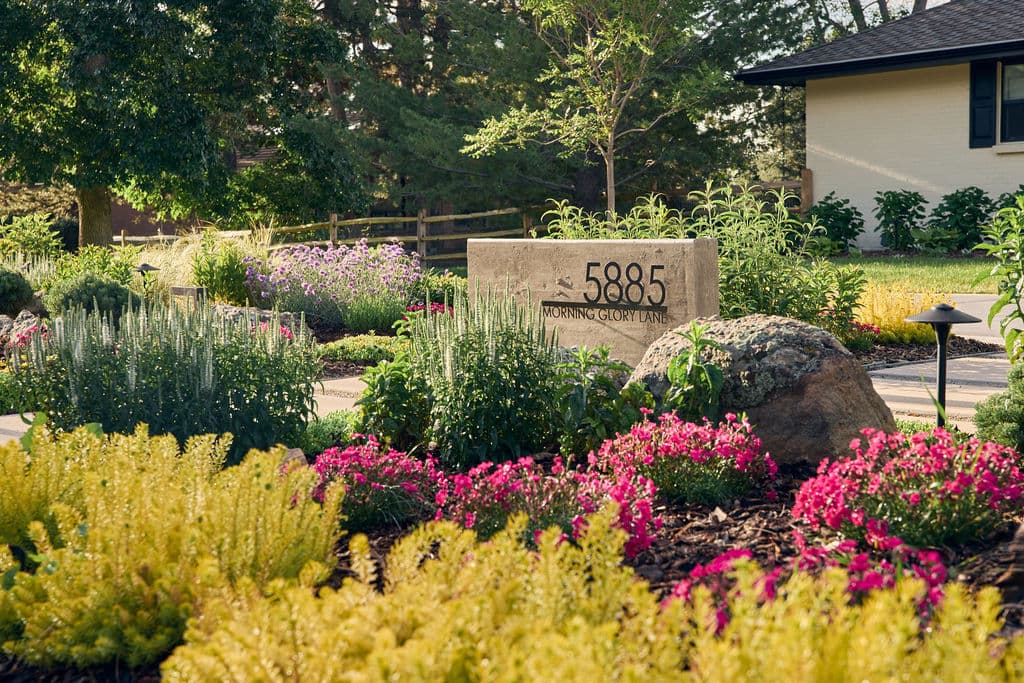Beautiful garden with colorful flowers and a stone marker displaying "5885 Morning Glory Lane."