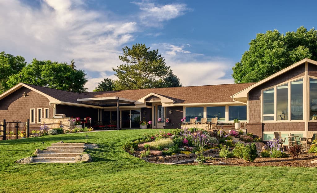 Charming modern house with landscaped garden and stone steps under a blue sky.