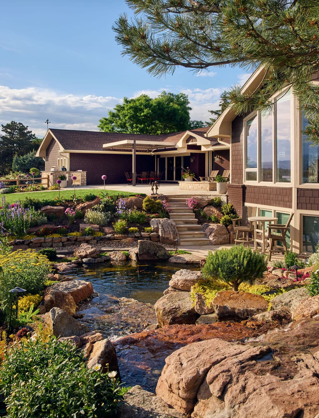 Beautiful landscaped garden with a pond, rocks, and a modern home in the background.