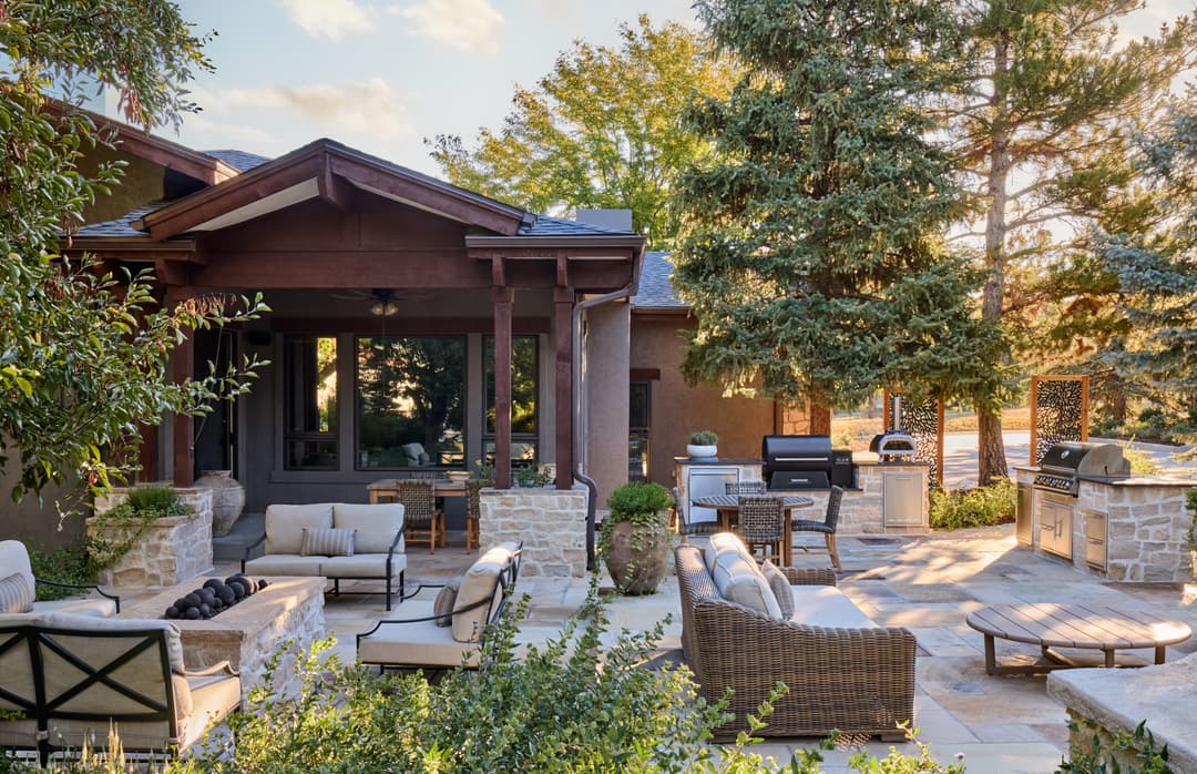 Elegant outdoor patio with stone seating, grills, and lush greenery for a cozy dining experience.