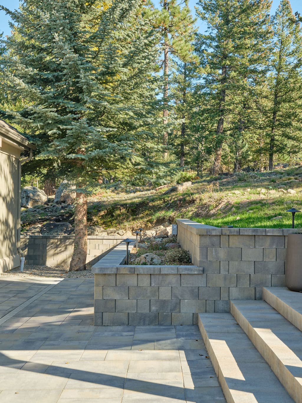 Paved outdoor space with stone steps, surrounded by trees and natural landscape.