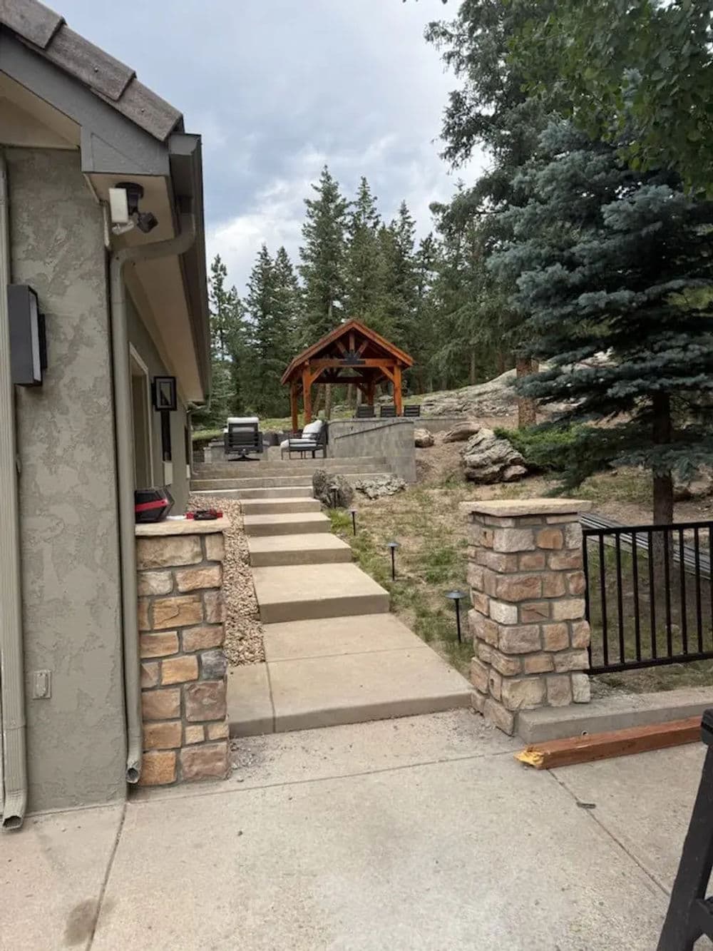 Pathway leading to a wooden gazebo surrounded by trees and landscaped yard.
